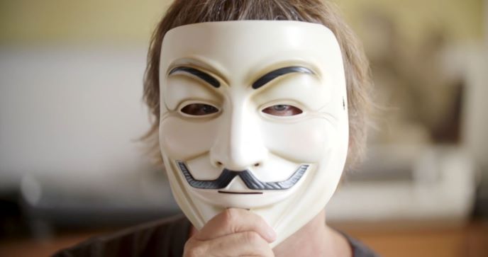 A person holding "Anonymous" mask