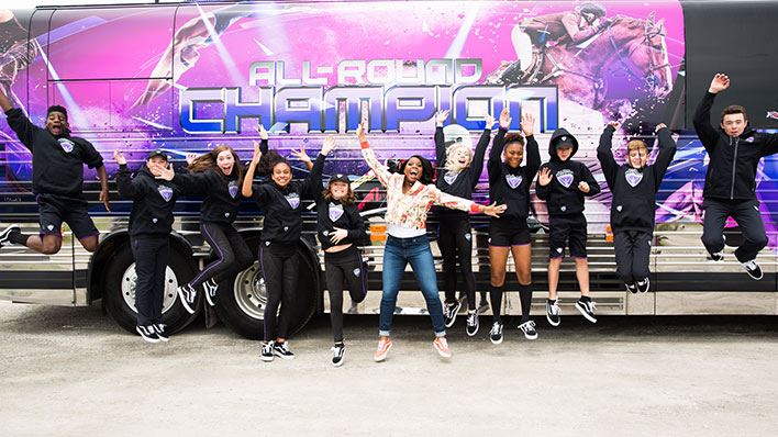 People posing in front of an All-Round Champion bus