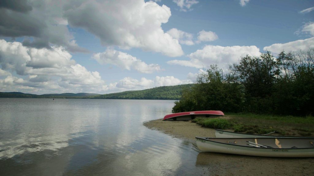Photo of serene lake with two empty canoes on beach