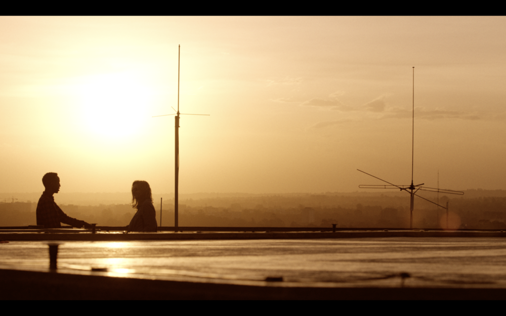 Two silhouetted figures stand before a sunset