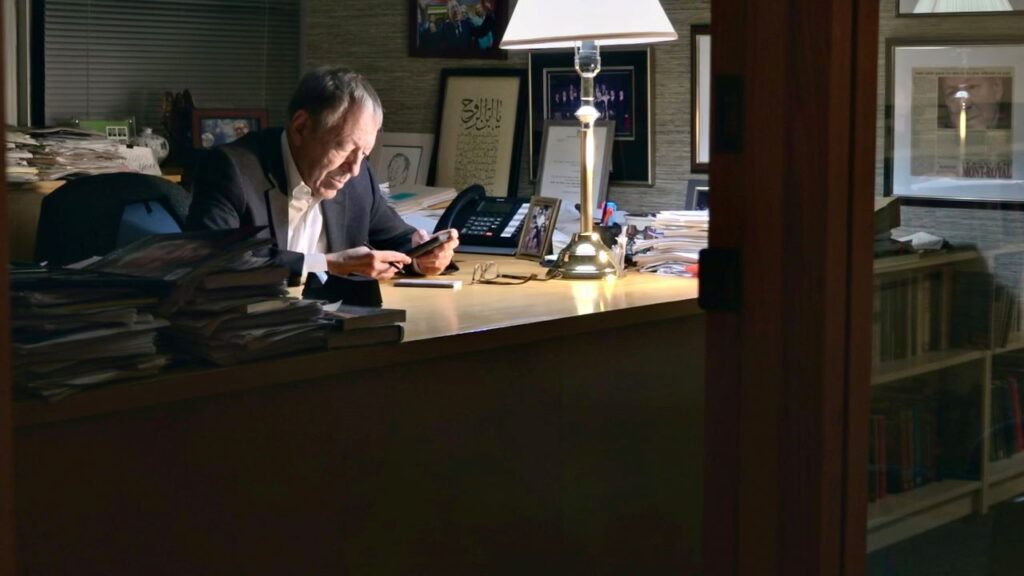 A businessman sitting at a desk looking at a mobile device