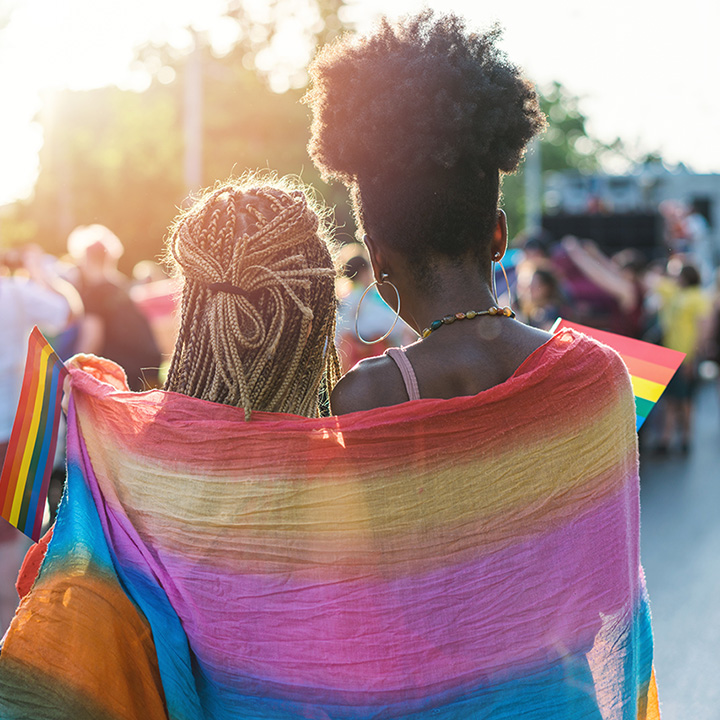 Young couple hugging with rainbow scarf at the pride event.