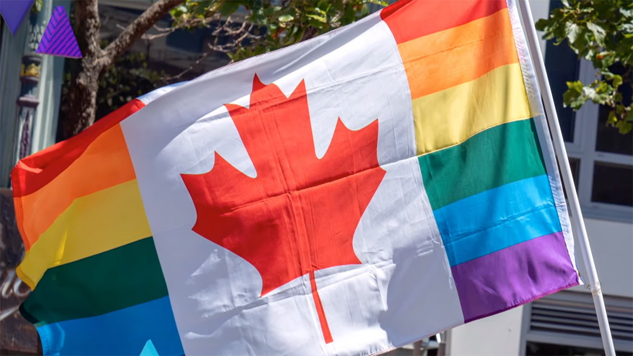 Canadian flag combined with rainbow Pride stripes waving outdoors.